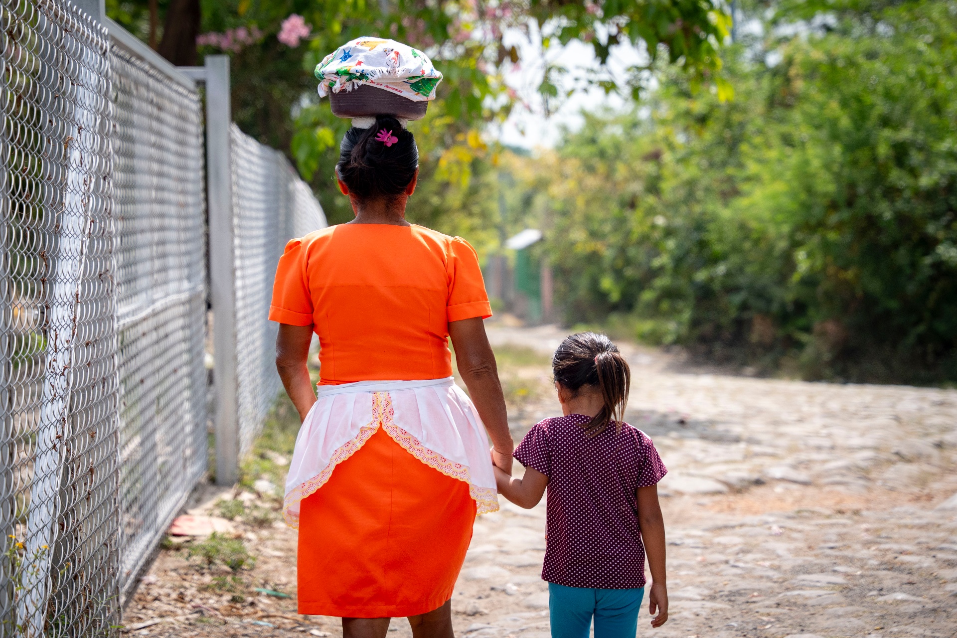 Mother and daughter walking down a sunlit road in El Salvador
